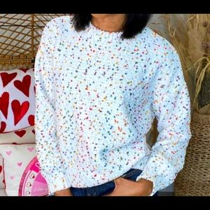 Adorable cream sweater with confetti designs.